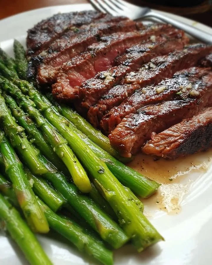 Herb Grilled Steak with Garlic Asparagus Delicious herb grilled steak served with garlic asparagus on a plate.